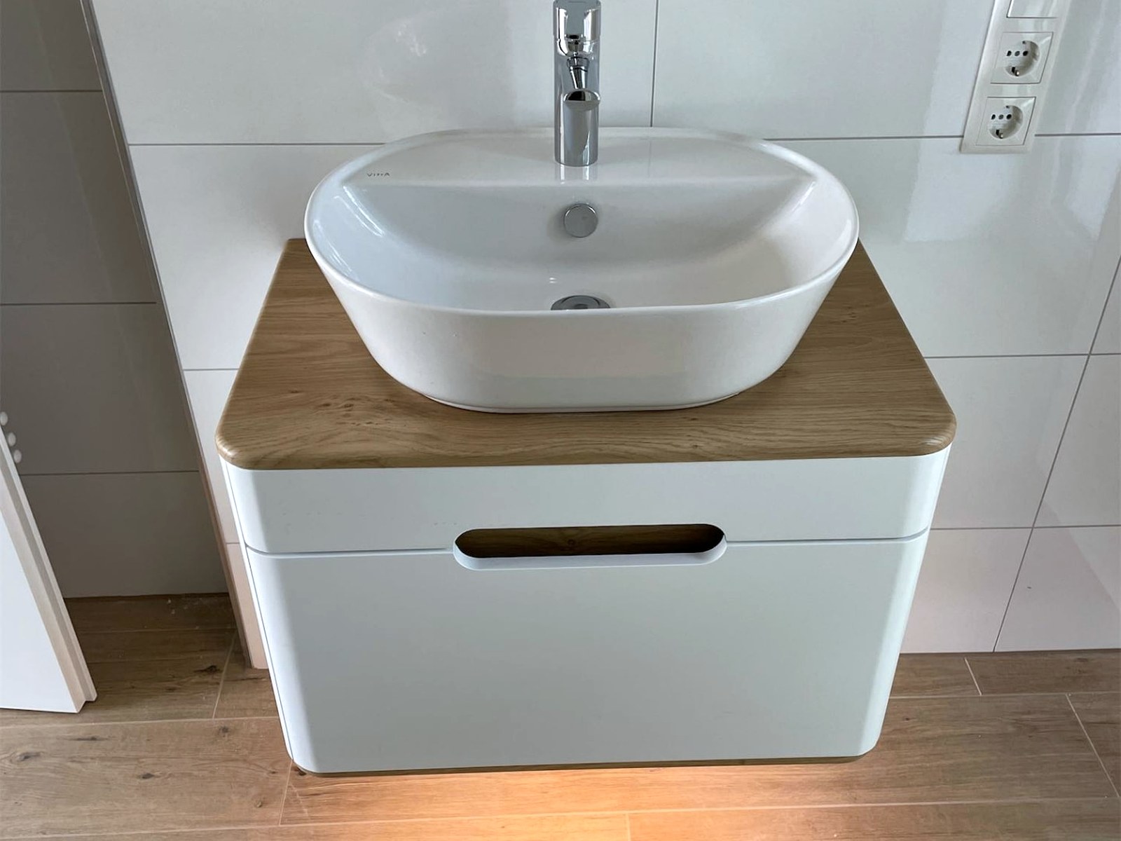 Aufsatzwaschbecken auf einem Unterschrank mit Eichenplatte vor weißen Fliesen