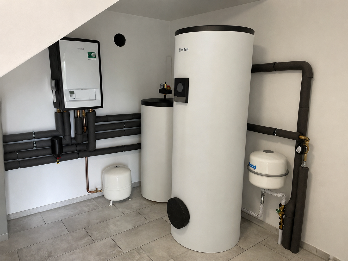 Technikraum im Neubau mit Wandgerät, Trinkwasserspeicher, Pufferspeicher, Ausdehnungsgefäßen und gedämmter Verrohrung