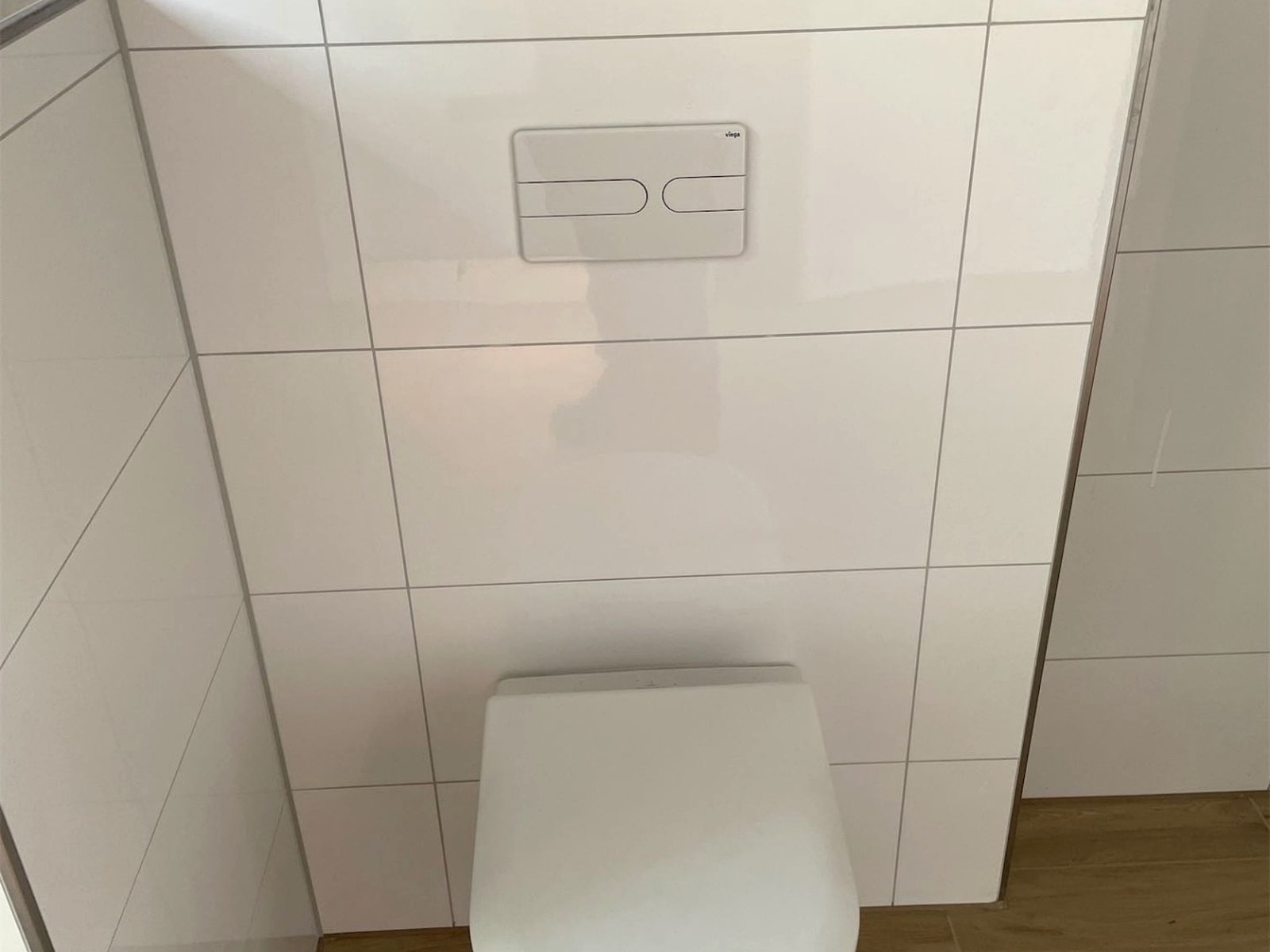 Wand-WC vor einer Vorwandinstallation mit Betätigungsplatte und Holzablage