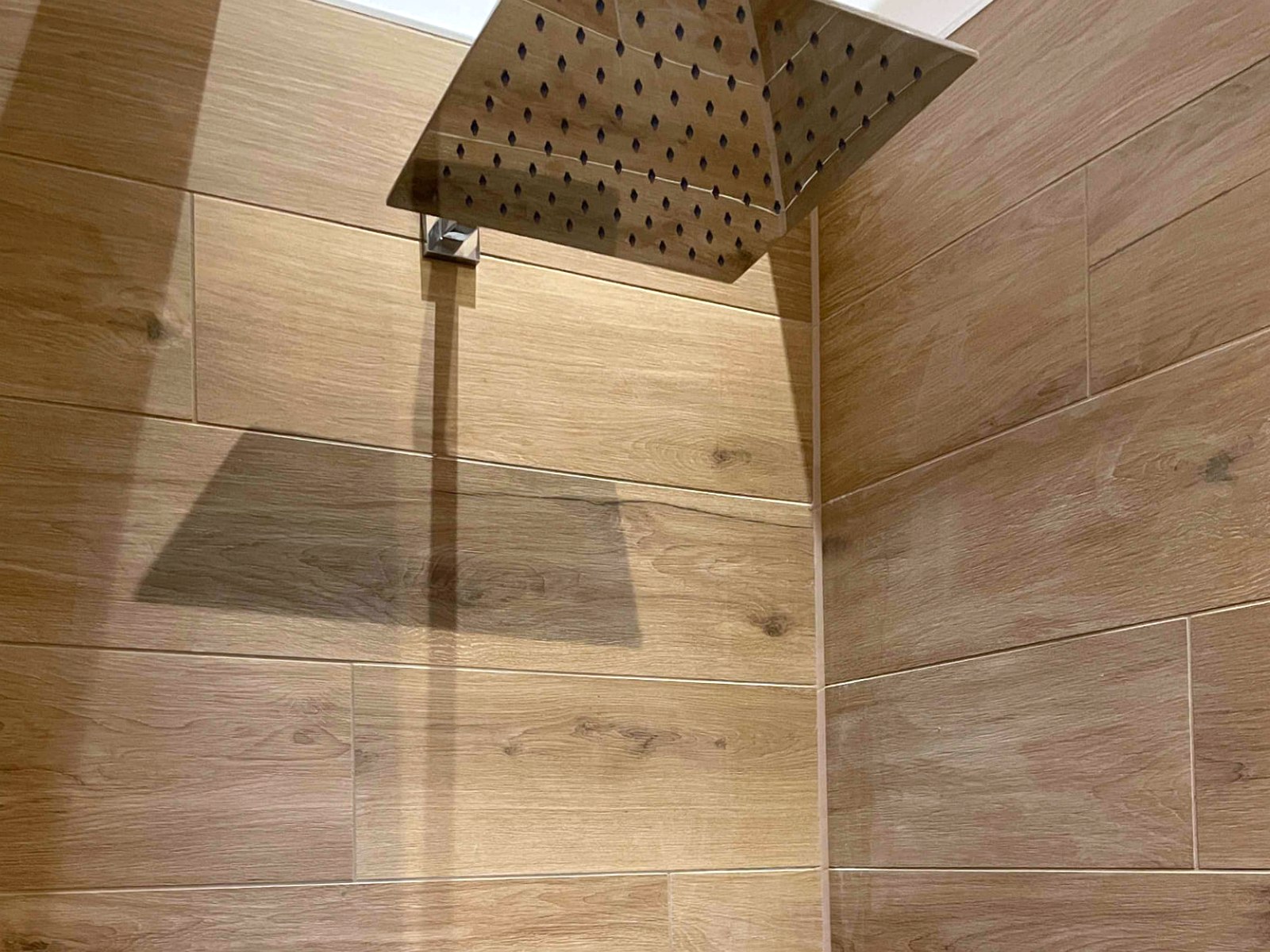 Dusche mit Decken-Regenbrause und großformatigen Fliesen in Holzoptik