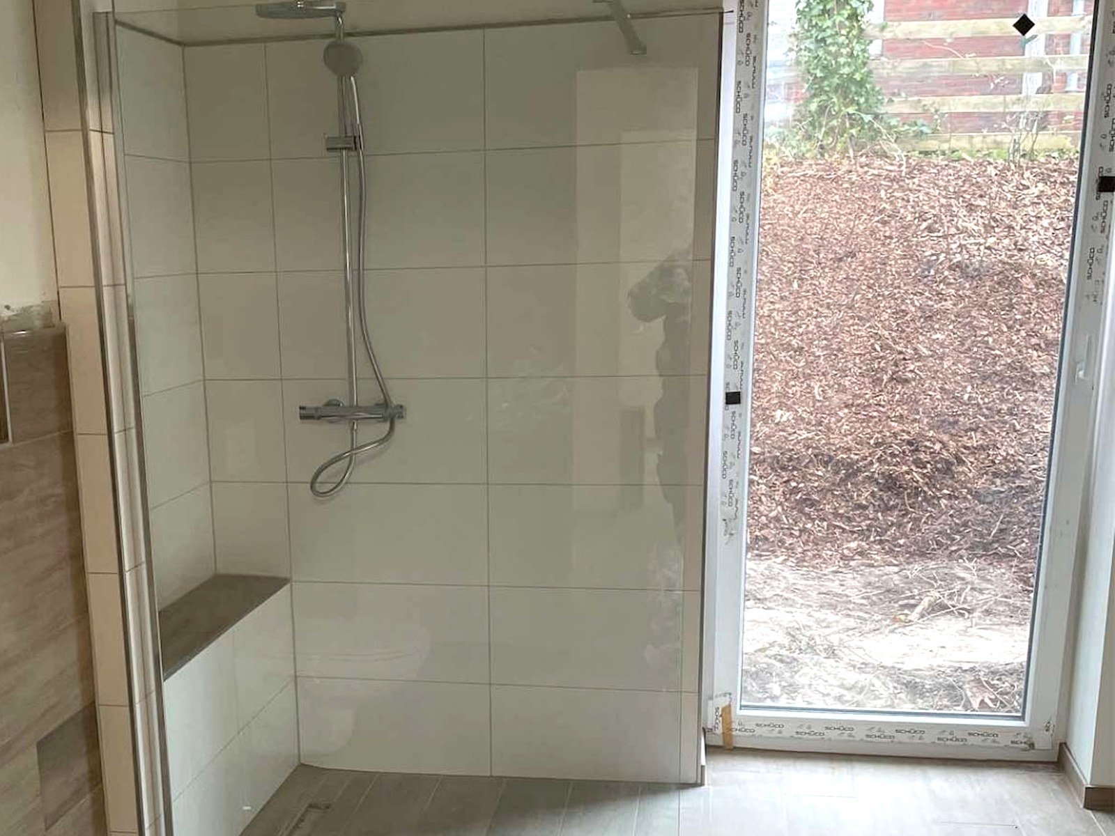 Fertiges Bad mit Walk-in-Dusche, Sitzbank, Wand-WC und bodentiefem Fenster