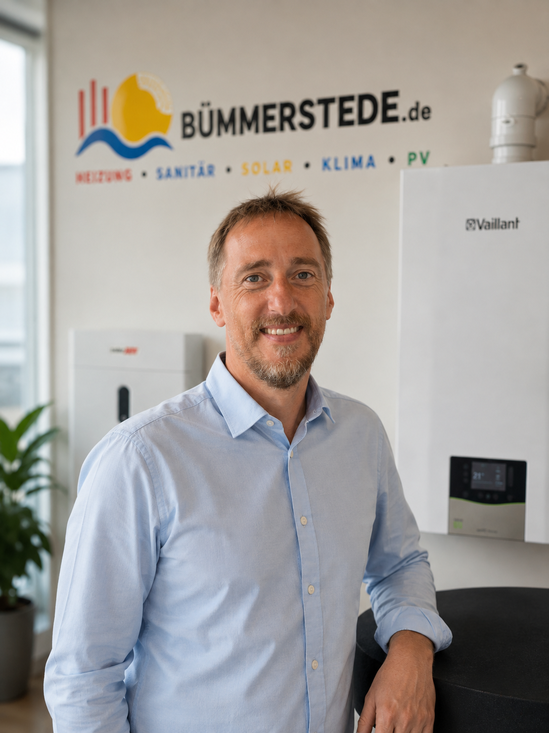 Thomas Bümmerstede, Geschäftsführer der BÜMMERSTEDE GmbH, in der Ausstellung in Varel vor Wandheizgerät und Stromspeicher